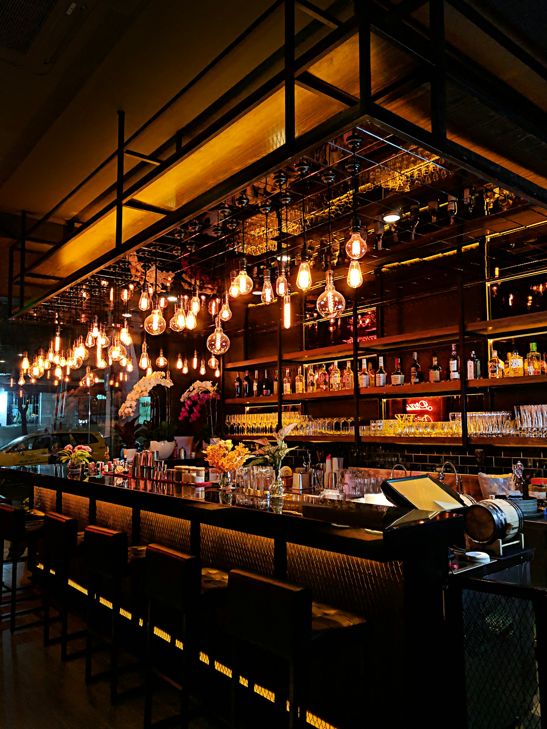 Dim wine bar interior with hanging Edison bulbs and a long marble counter